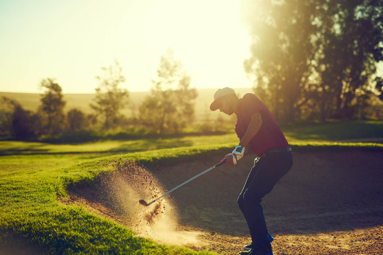 golfer chipping out of bunker