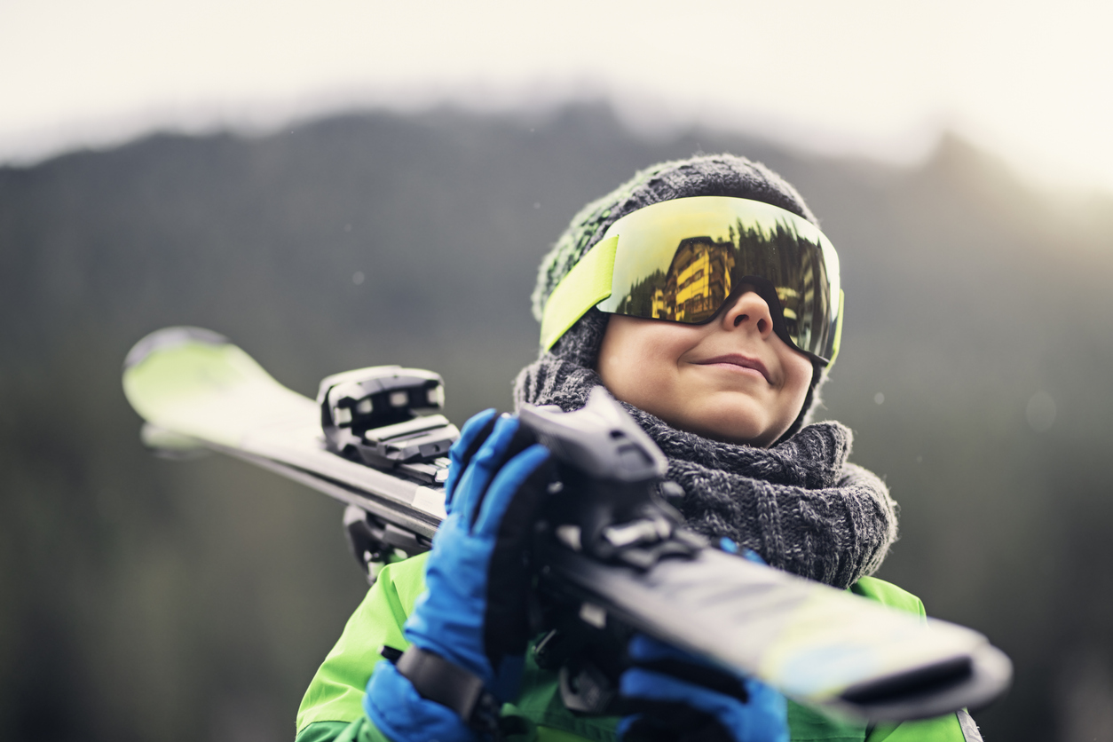 Portrait of a little skier carrying his skis stock photo