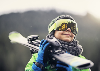 Portrait of a little skier carrying his skis stock photo