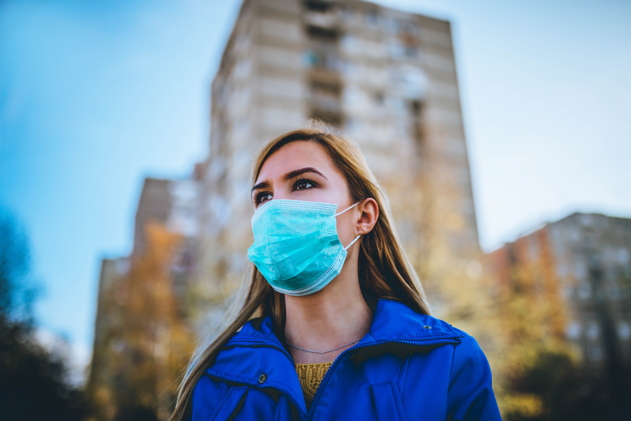 woman wearing surgical mask while walking in public area