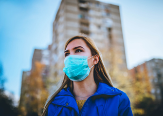 woman wearing surgical mask while walking in public area