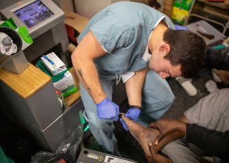 medical student provides foot care to homeless person at Franciscan House of Joseph and Mary