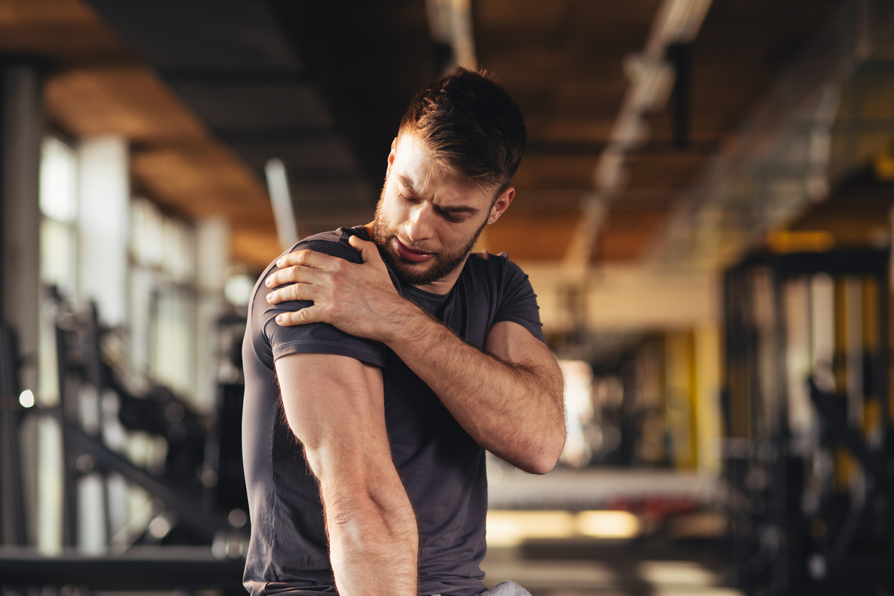 man in the gym looking at his injured shoulder